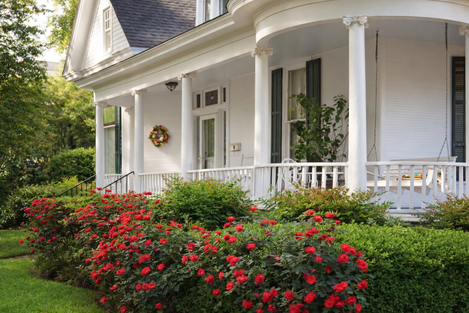 Well-maintained Southern style home porch in West Tennessee with white columns and landscaped front yard.